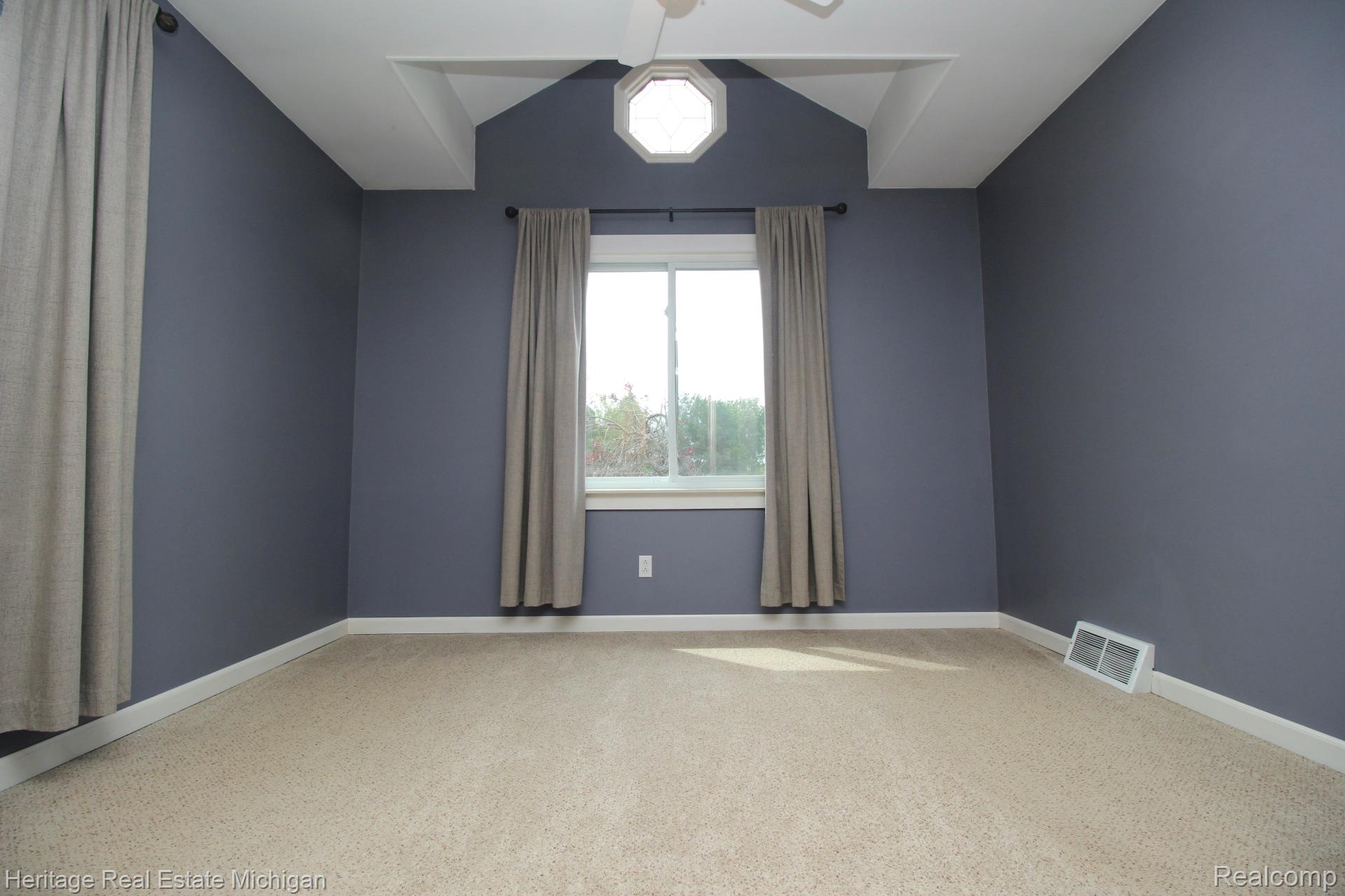 15352 South Duffield Road Byron, MI 48418 - Photo 21 of 47 Carpeted interior space featuring a window with exterior visibility, tray ceiling detail, an octagonal window element, and white trim