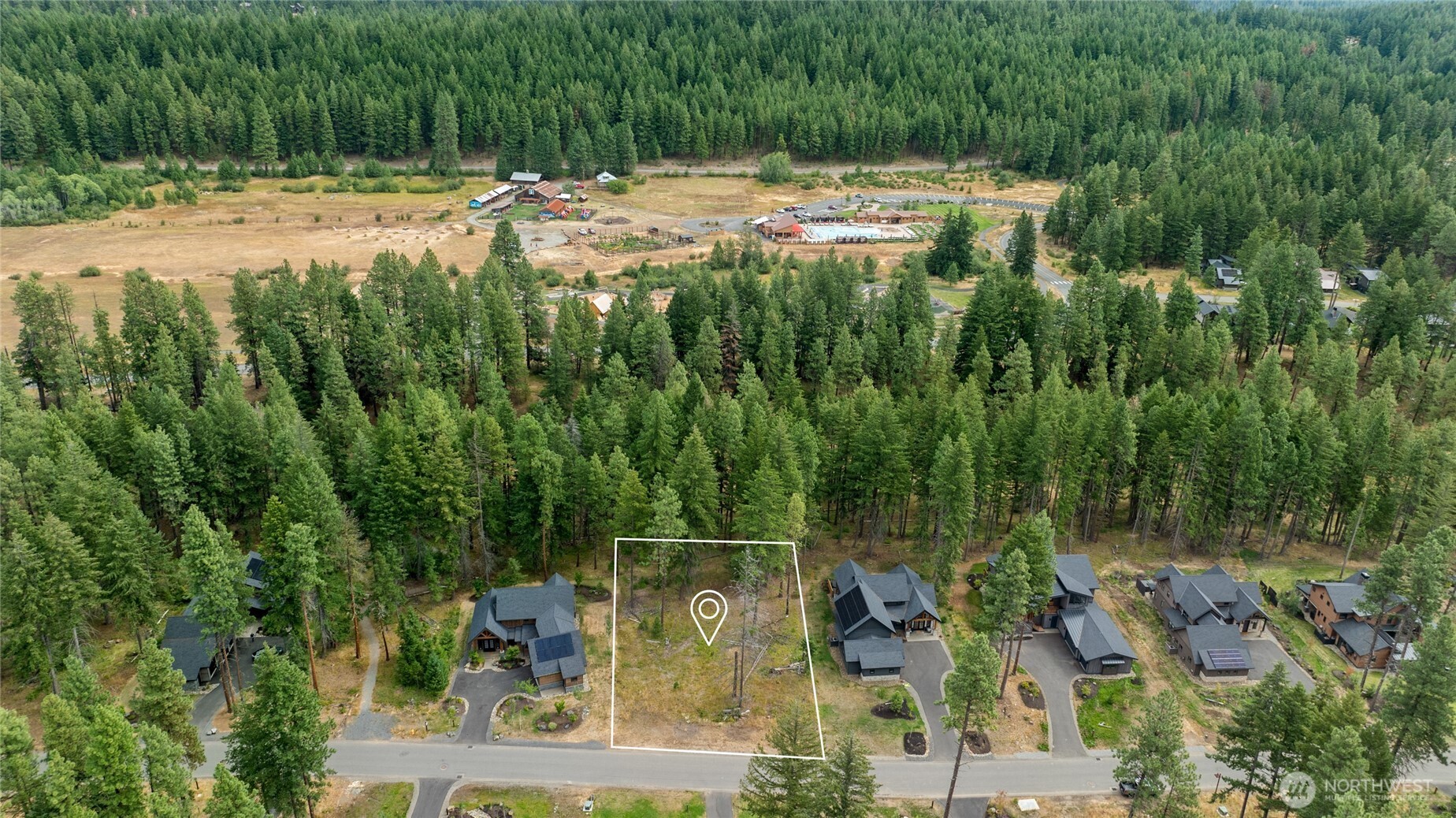 an aerial view of residential house with outdoor space and trees all around