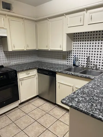 a white kitchen with granite countertop a sink and a stove
