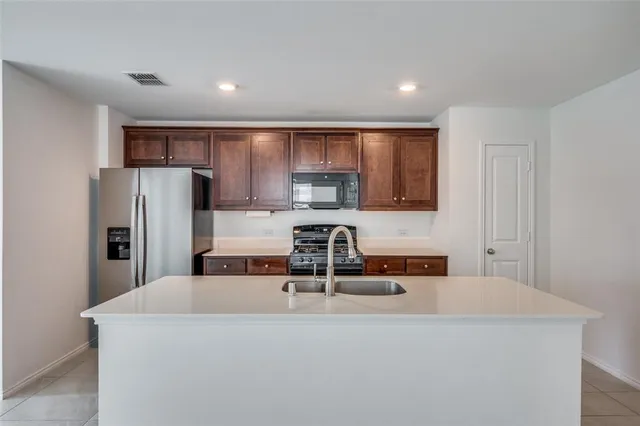 a kitchen with kitchen island a sink a refrigerator and a stove
