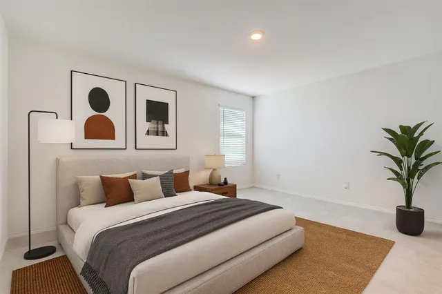 a bedroom with a large bed and a potted plant