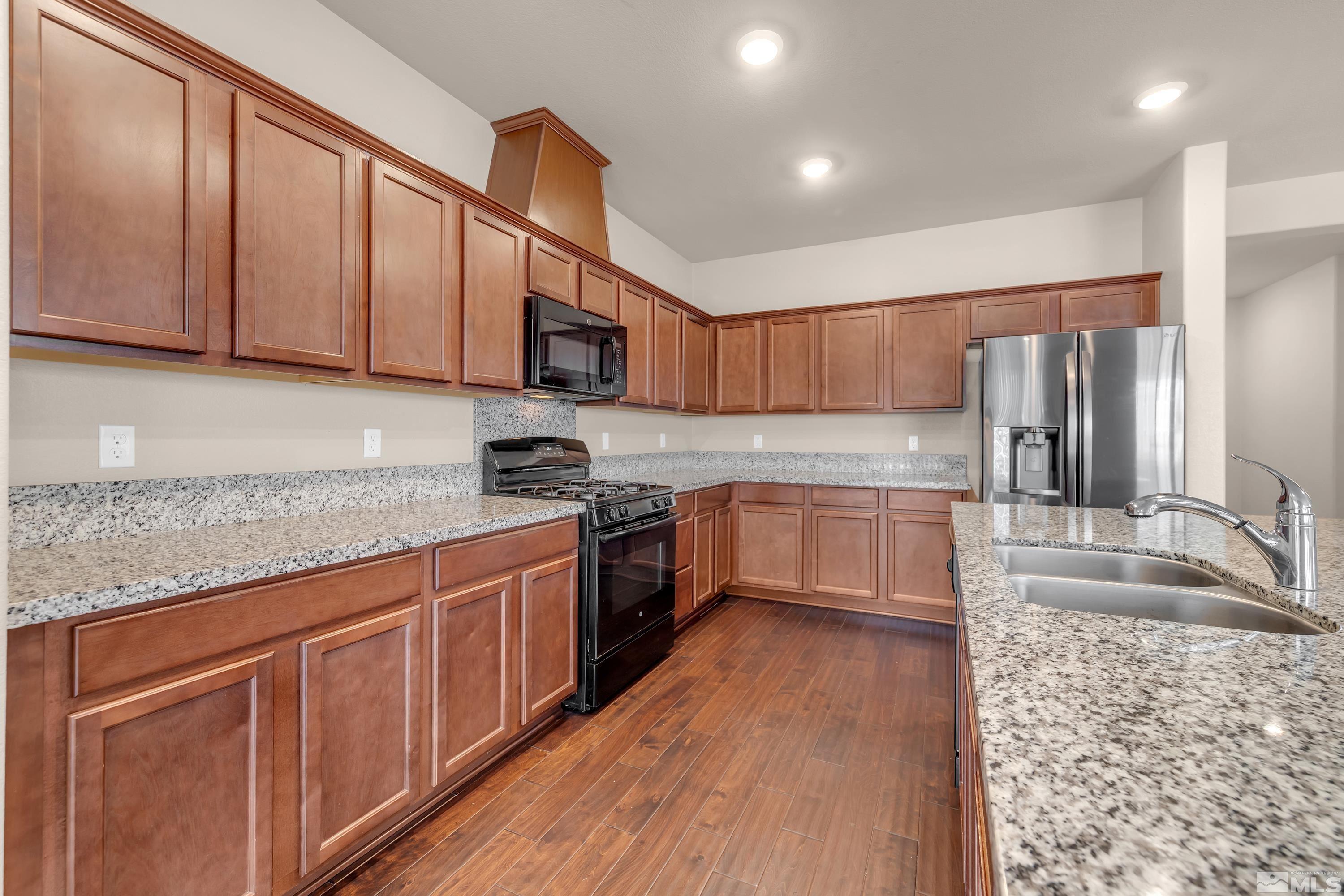 9352 Bay Drive Reno, NV 89506 - Photo 9 of 37 a kitchen with stainless steel appliances granite countertop wooden cabinets a stove top oven a sink and dishwasher a refrigerator with wooden floor