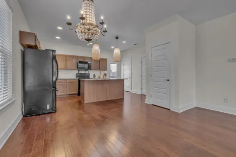 a kitchen with stainless steel appliances granite countertop a sink a stove a refrigerator cabinets and chairs