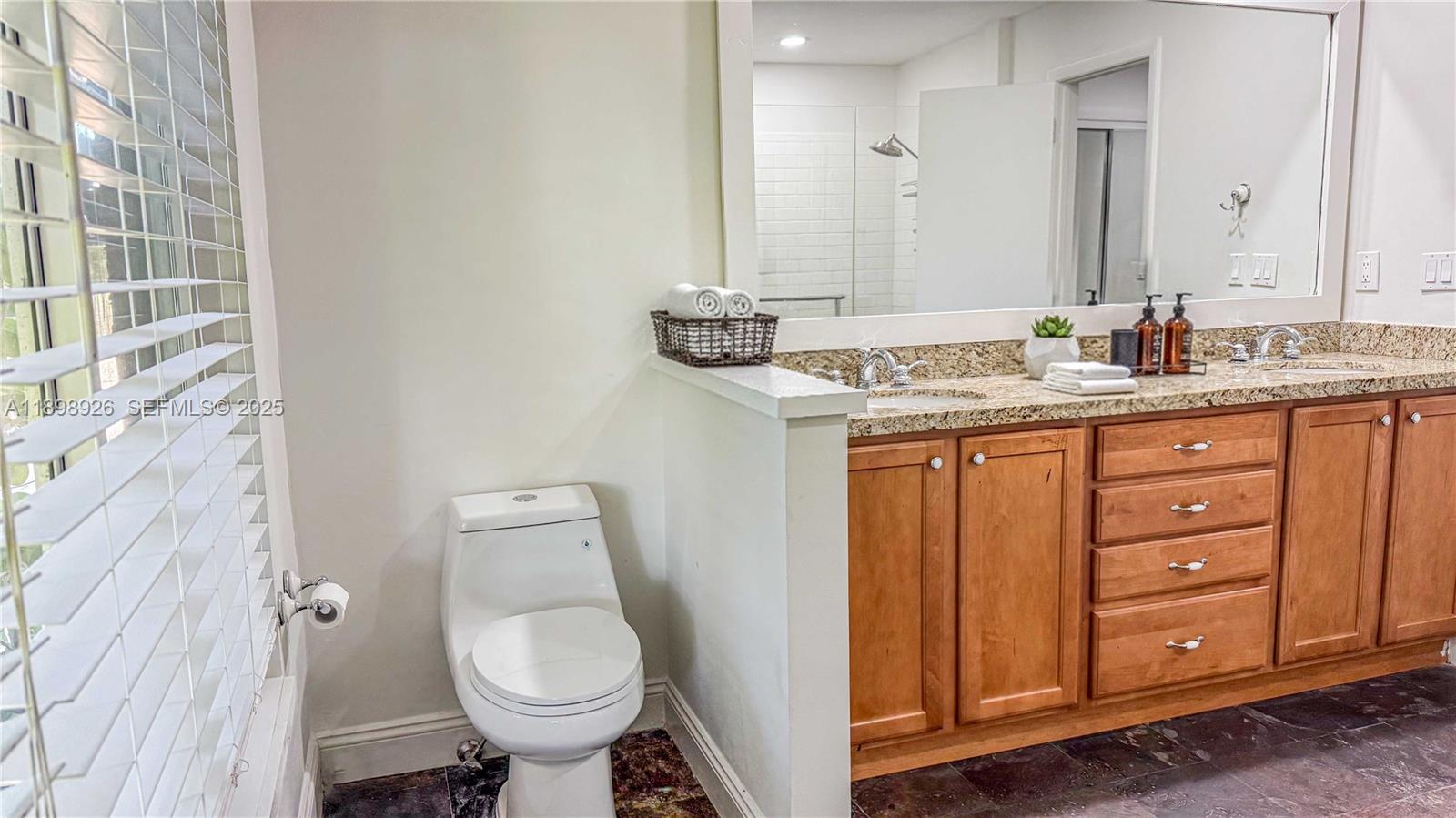 10134 Boca Woods Lane, Unit 10134 Boca Raton, FL 33428 - Photo 6 of 17 a bathroom with a granite countertop toilet sink and mirror