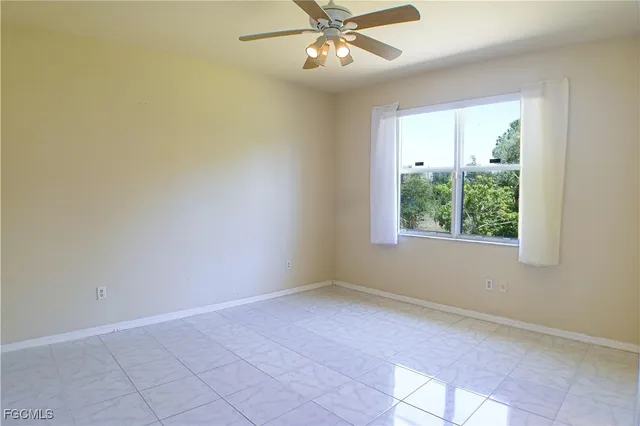 an empty room with a chandelier fan and windows