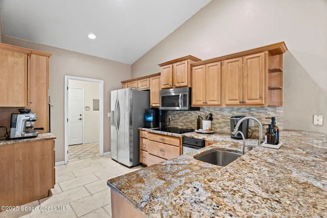 a kitchen with stainless steel appliances granite countertop a stove a sink and a refrigerator