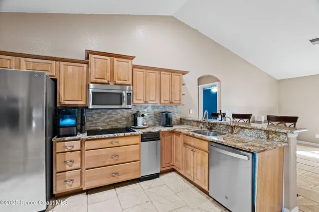 a kitchen with stainless steel appliances granite countertop a sink stove and refrigerator