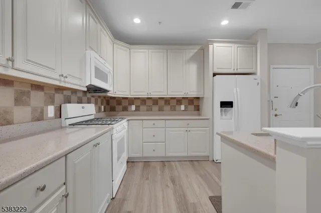 a kitchen with white cabinets and white appliances