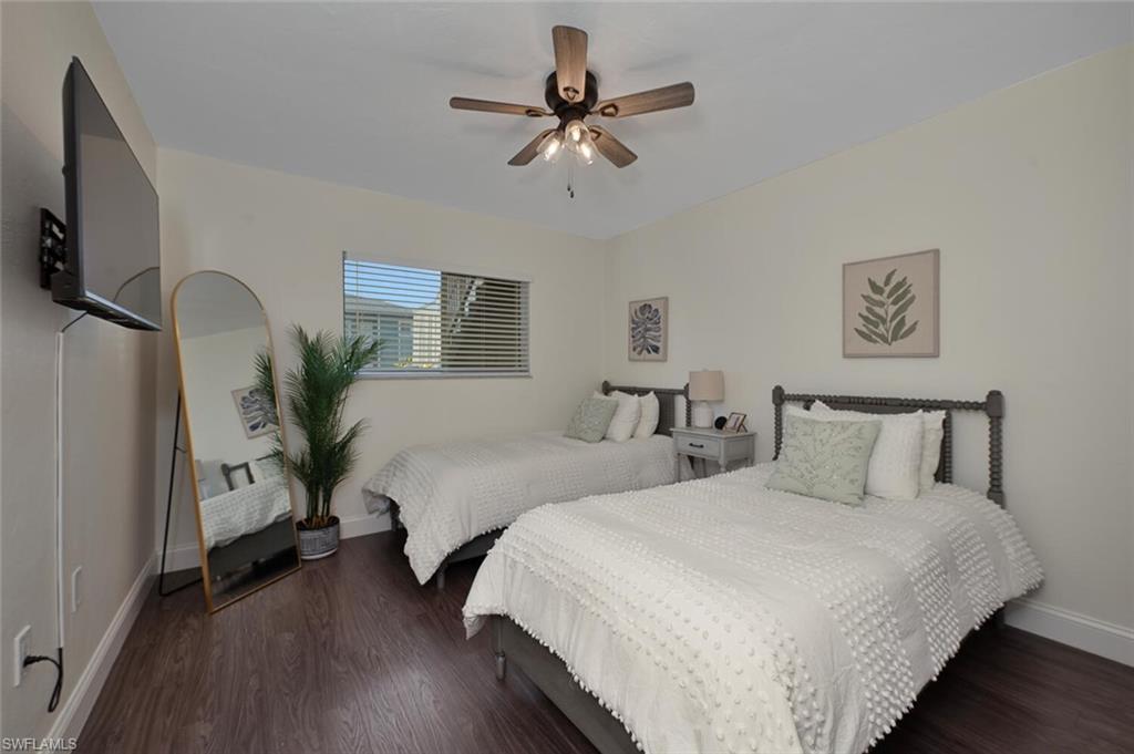 154 Cypress Way East, Unit 1102 Naples, FL 34110 - Photo 9 of 12 a bedroom with two separate beds and a chandelier
