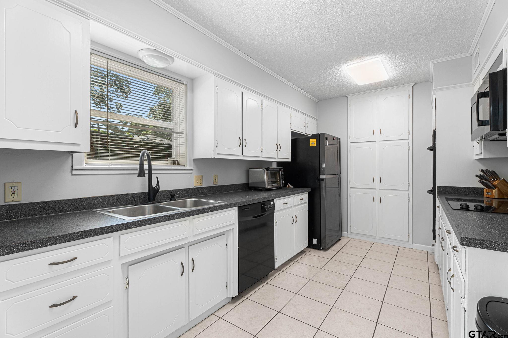 8224 Purdue Drive Tyler, TX 75703 - Photo 12 of 39 a kitchen with granite countertop white cabinets white appliances a sink and a counter top space