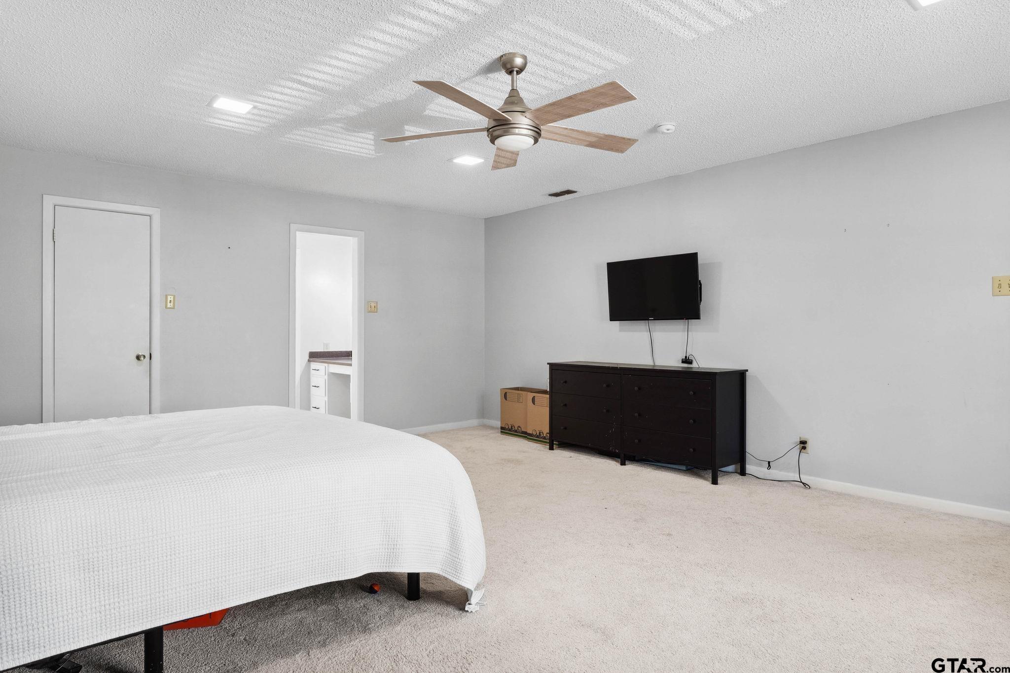 8224 Purdue Drive Tyler, TX 75703 - Photo 17 of 39 a bedroom with a bed and a flat tv screen on dresser