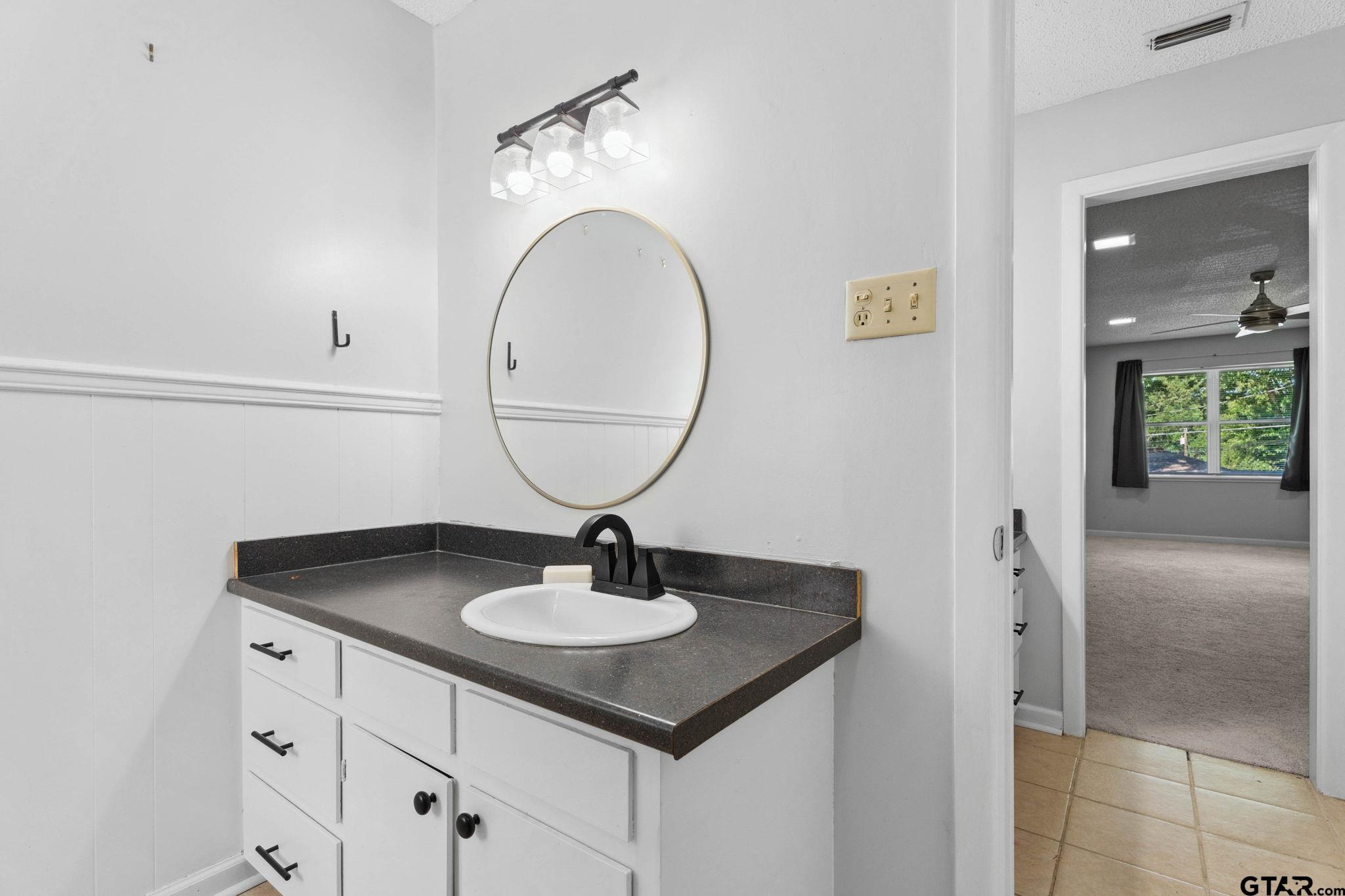 8224 Purdue Drive Tyler, TX 75703 - Photo 21 of 39 a sink with a mirror and wooden floor