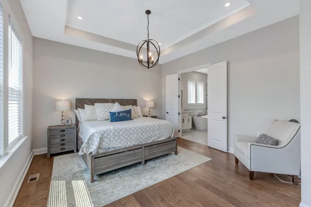 a bedroom with a large bed a flat tv screen and a dresser