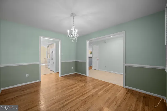 a view of empty room with wooden floor and chandelier
