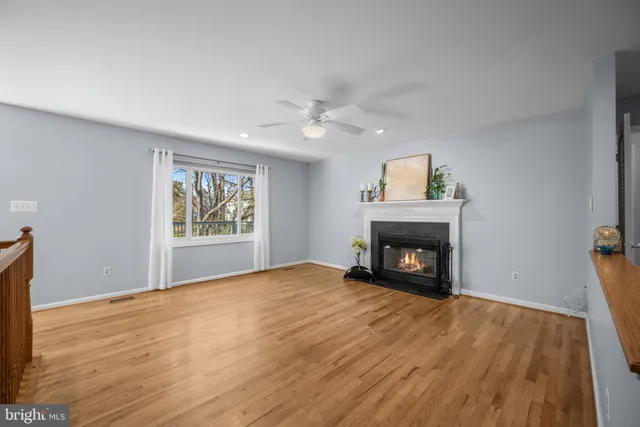 a view of an empty room with wooden floor fireplace and a window