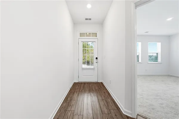 a view of a hallway with wooden floor and a bathroom