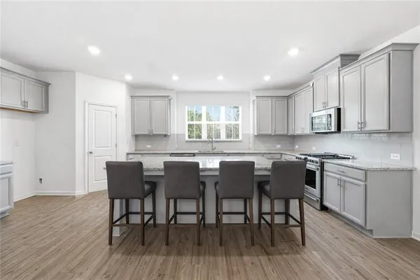 a kitchen with stainless steel appliances granite countertop wooden floor a dining table and chairs