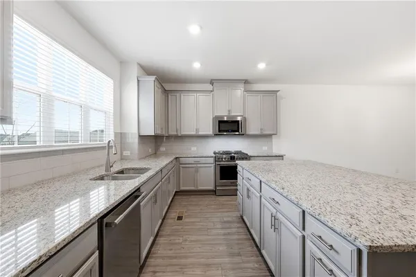 a large kitchen with stainless steel appliances granite countertop a sink stove and cabinets