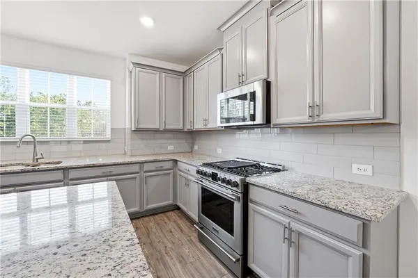 a kitchen with stainless steel appliances granite countertop a stove a sink and a white cabinets