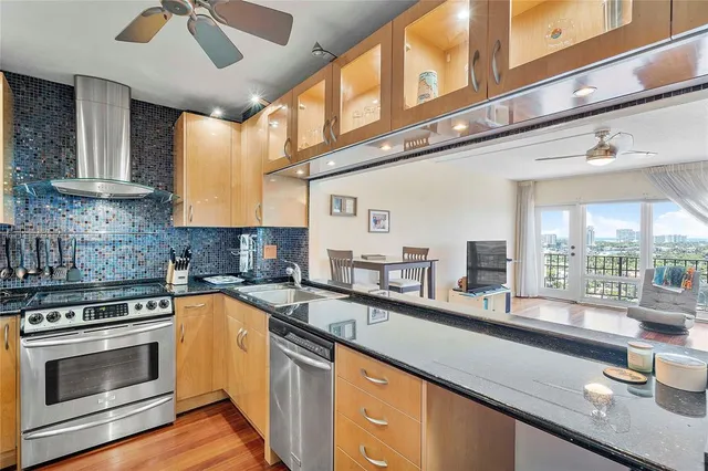 a kitchen with stainless steel appliances granite countertop a sink a stove and a wooden floors