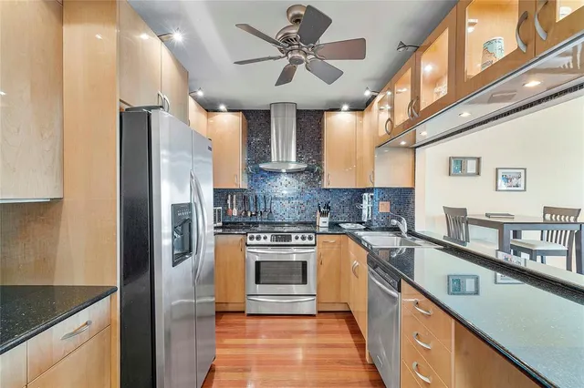 a kitchen with stainless steel appliances granite countertop a sink a stove and refrigerator