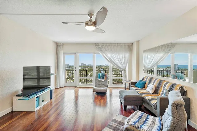 a living room with furniture a flat screen tv and a floor to ceiling window