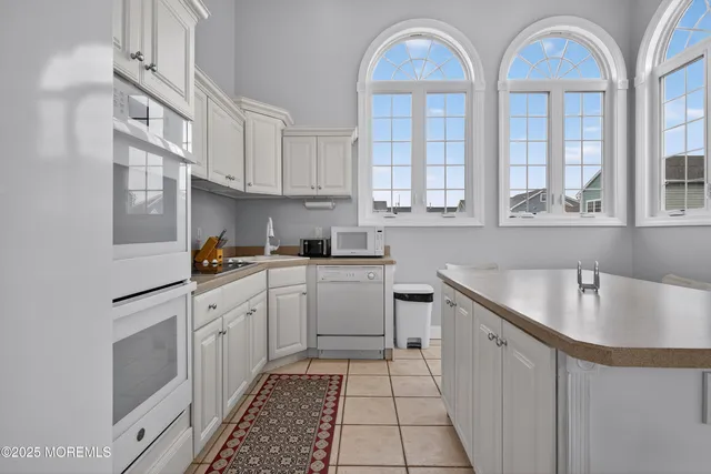 a kitchen that has a lot of white cabinets and a sink
