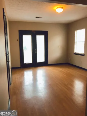 an empty room with wooden floor and windows