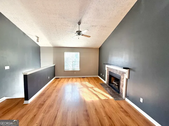 a view of empty room with a fireplace and wooden floor