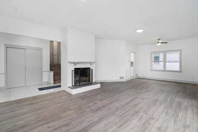 an empty room with wooden floor a fireplace and windows