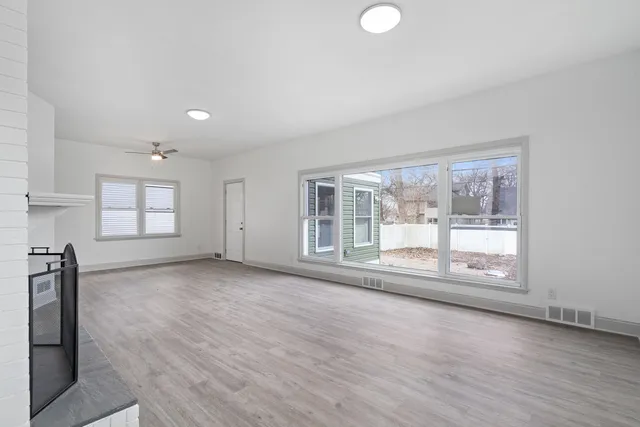 a view of an empty room with a window and wooden floor