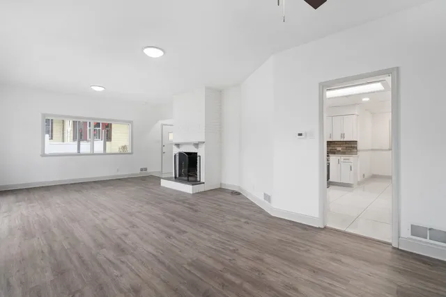 a view of empty room with wooden floor and a window