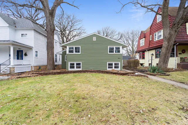 a view of a house with a yard and large tree