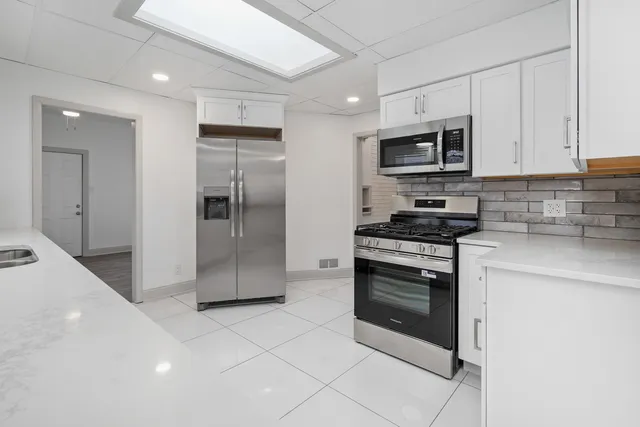 a kitchen with stainless steel appliances granite countertop a refrigerator and a stove top oven
