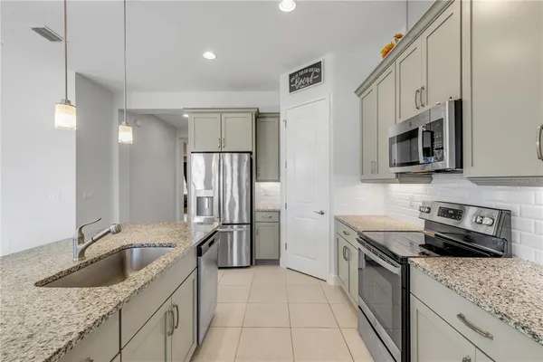 a kitchen with stainless steel appliances granite countertop a sink a stove and a refrigerator