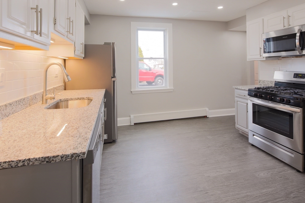 259 Calvary Street, Unit 1 Waltham, MA 02453 - Photo 5 of 27 a kitchen with stainless steel appliances granite countertop a sink and a stove