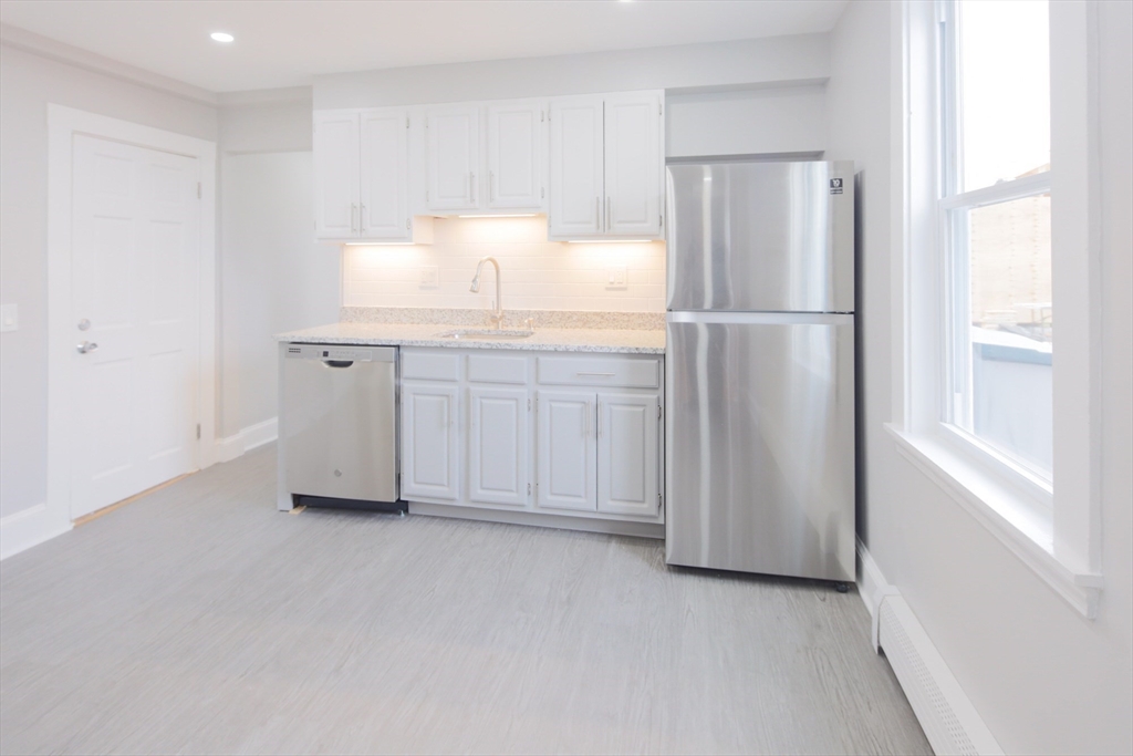 259 Calvary Street, Unit 1 Waltham, MA 02453 - Photo 6 of 27 a kitchen with white cabinets and refrigerator