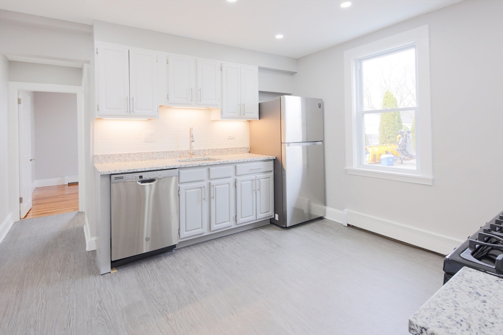 259 Calvary Street, Unit 1 Waltham, MA 02453 - Photo 7 of 27 a kitchen with stainless steel appliances a refrigerator sink and cabinets