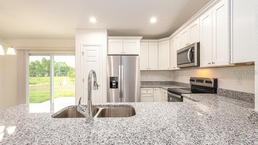 151 Malauka Road Ocklawaha, FL 32179 - Photo 15 of 29 a kitchen with stainless steel appliances granite countertop a stove a sink and a microwave