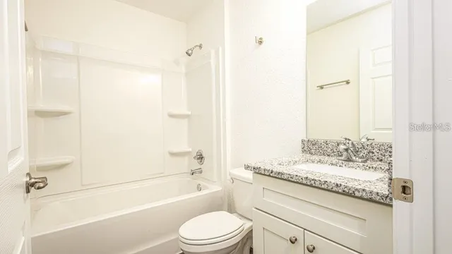 a view of an empty room with wooden floor ceiling fan