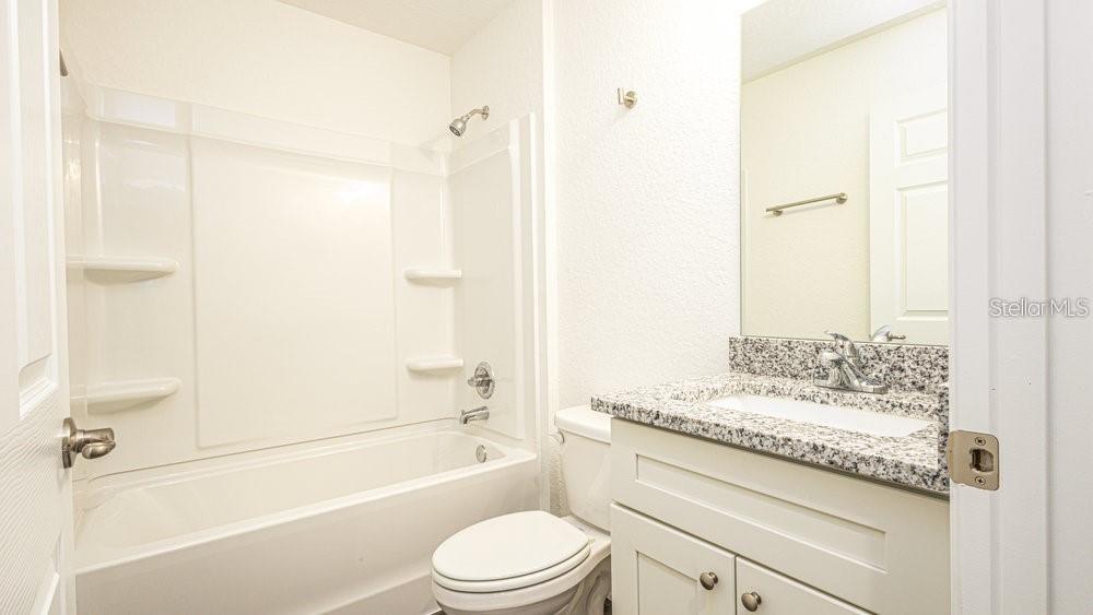 151 Malauka Road Ocklawaha, FL 32179 - Photo 17 of 29 a bathroom with a granite countertop white toilet a sink and a bathtub