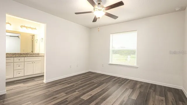 an empty room with wooden floor and ceiling fan