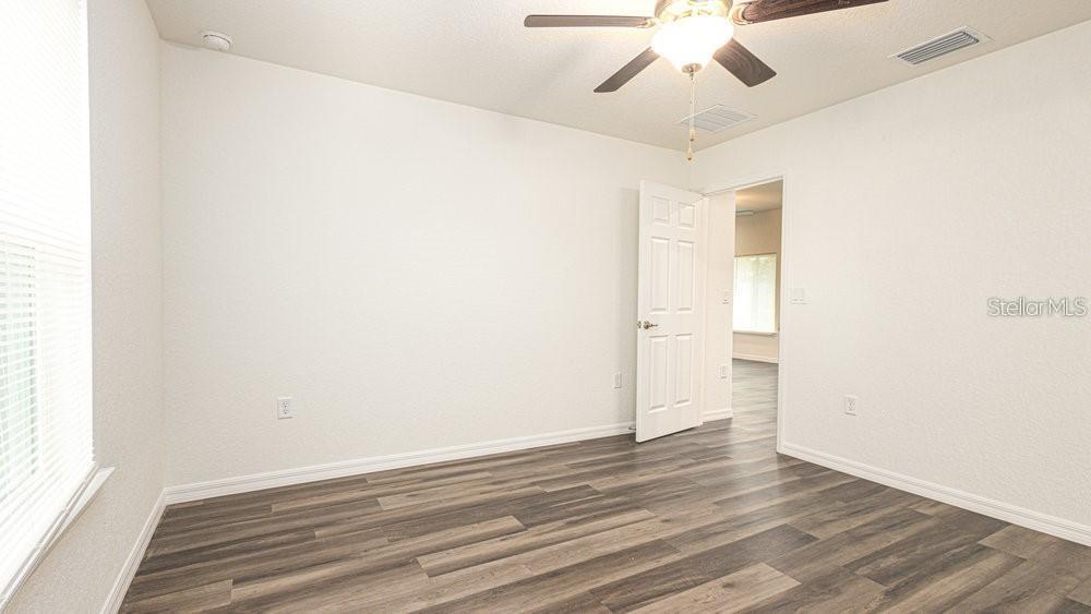 151 Malauka Road Ocklawaha, FL 32179 - Photo 24 of 29 an empty room with wooden floor and ceiling fan