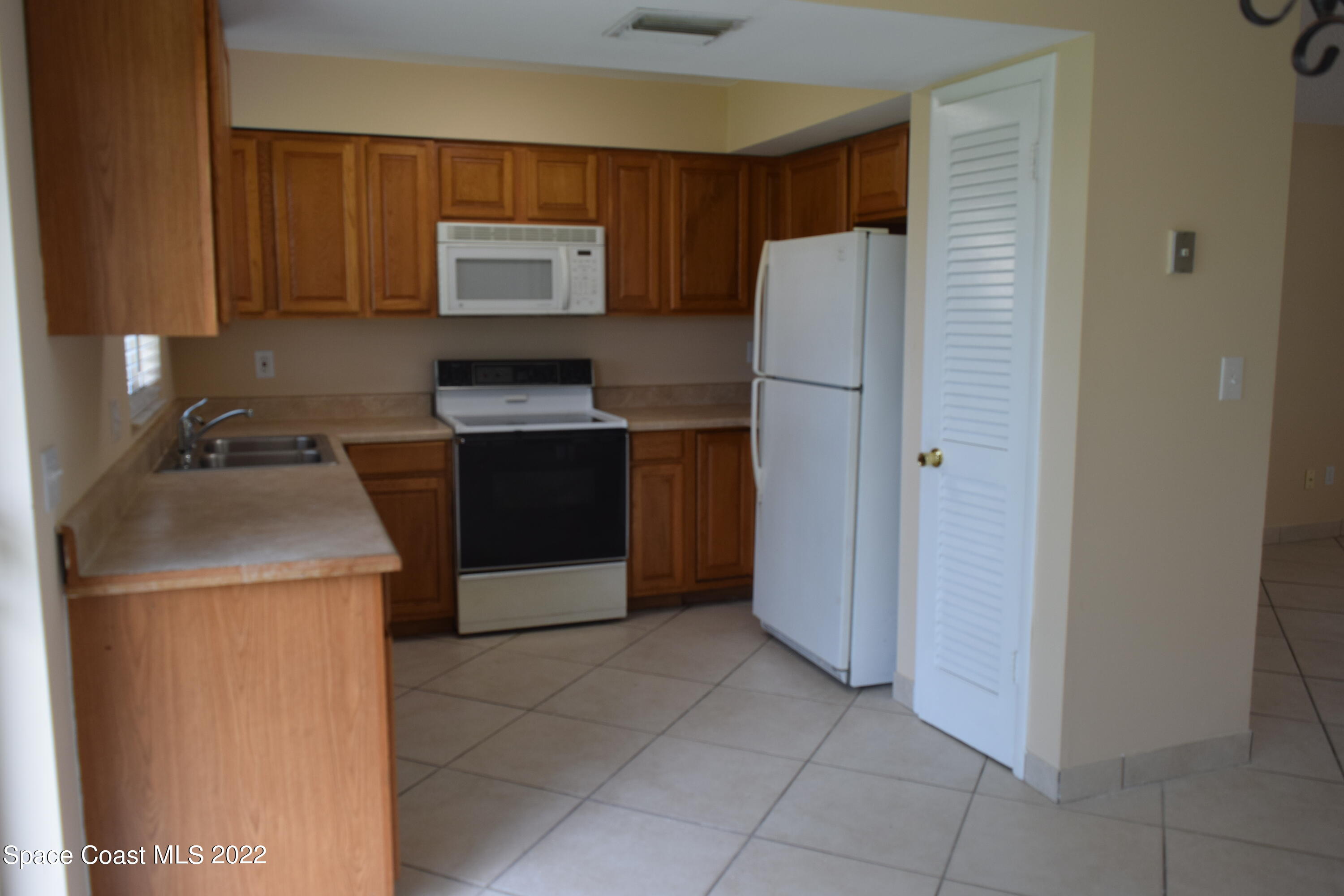 771 Cobblestone Lane Northeast Palm Bay, FL 32905 - Photo 8 of 30 a kitchen with a refrigerator sink and cabinets