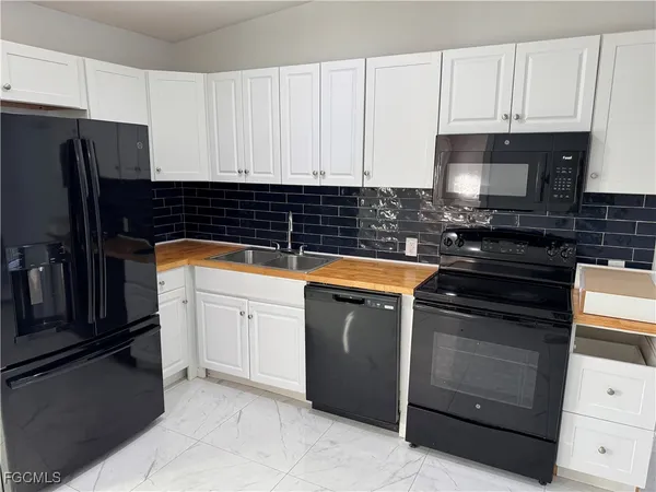 a kitchen with granite countertop white cabinets and stainless steel appliances