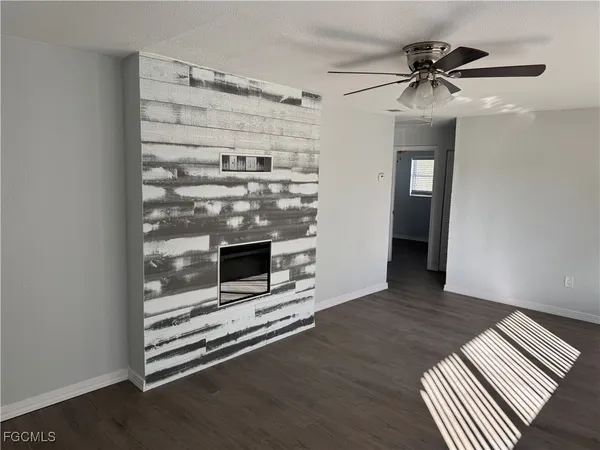 a view of an empty room with a fireplace and wooden floor