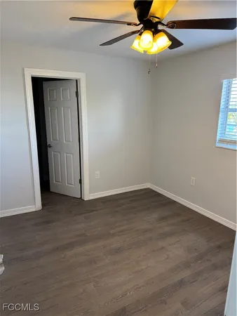 a view of an empty room with window and chandelier fan