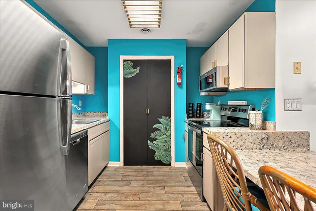 a kitchen with stainless steel appliances granite countertop a refrigerator a stove and a sink