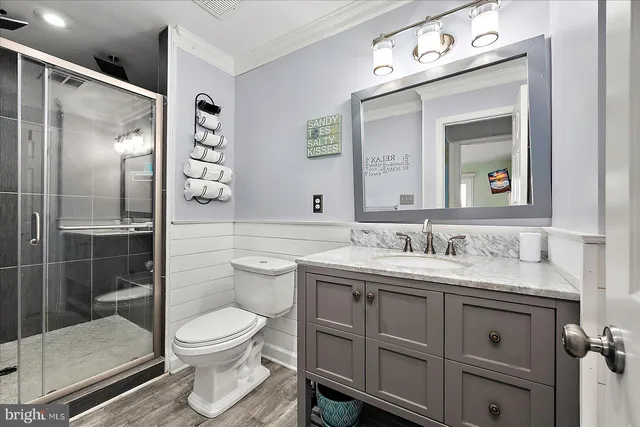 a bathroom with a toilet sink vanity granite and shower