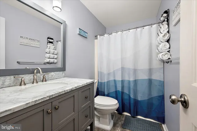 a bathroom with a granite countertop sink a toilet and a mirror